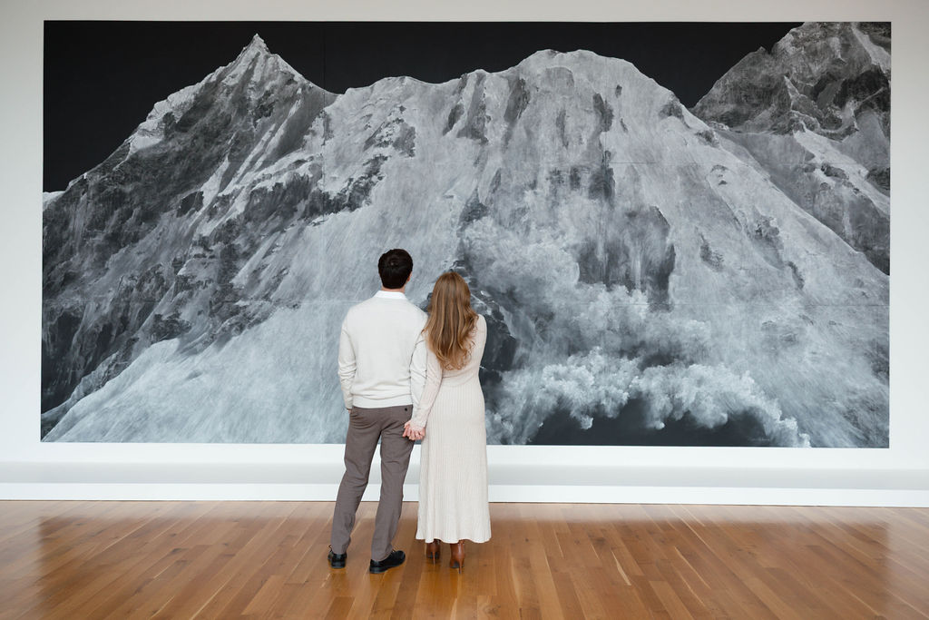 Katrina and Cody before a large mountain painting at the museum