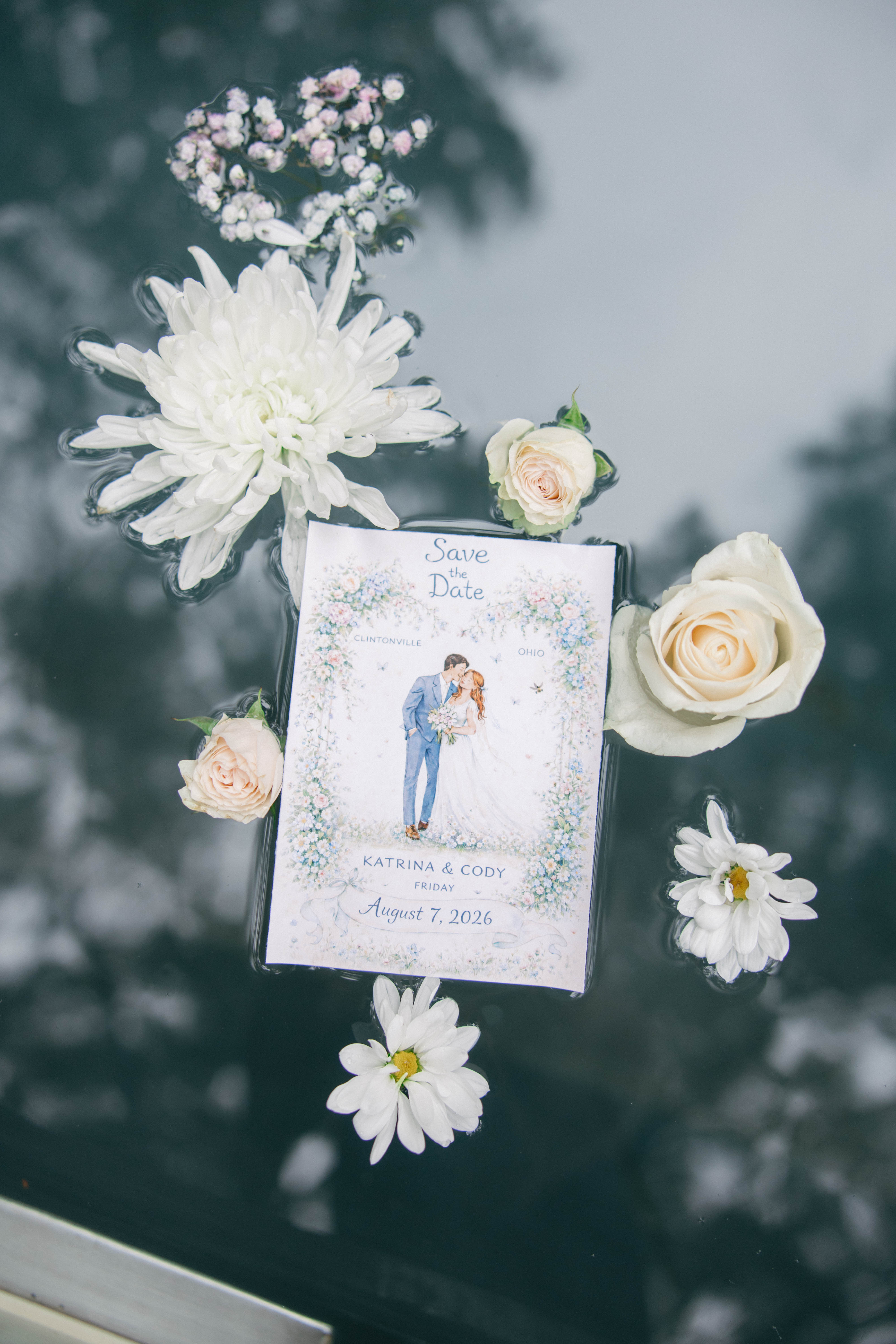 The save the date floating in the pool, surrounded by white flowers