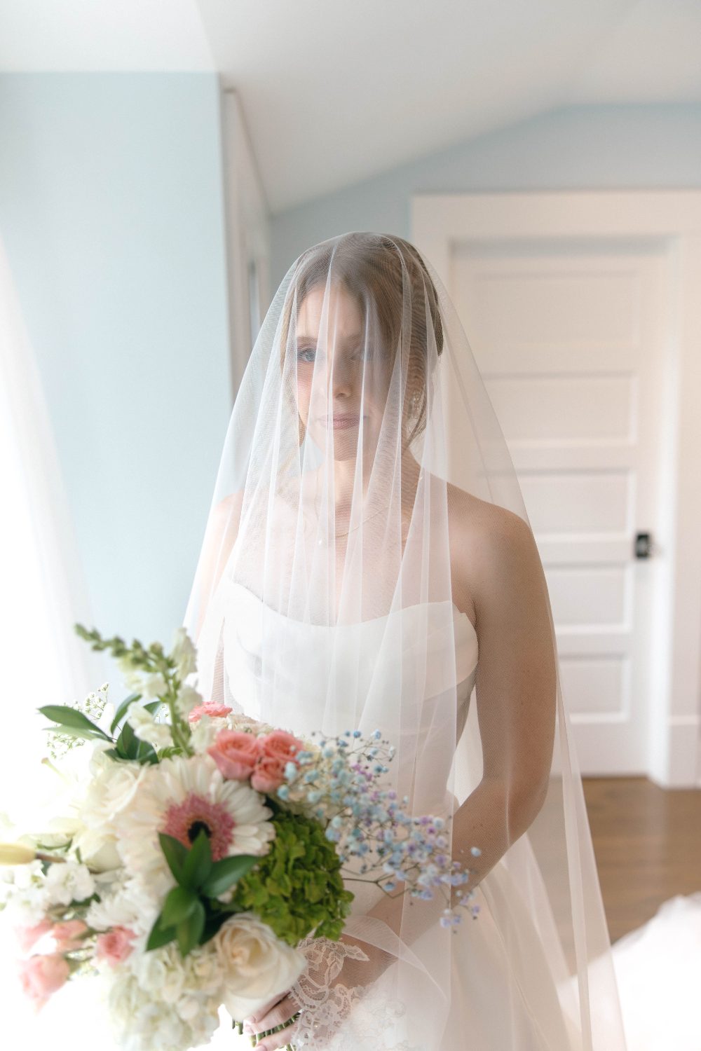 Katrina with her veil over her face, holding her bouquet